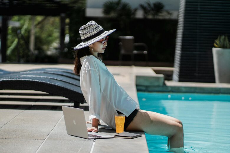 Digital nomad working on a laptop by the pool at a luxurious all-inclusive resort in Marrakech, Morocco, symbolizing productive remote work and exotic travel.
