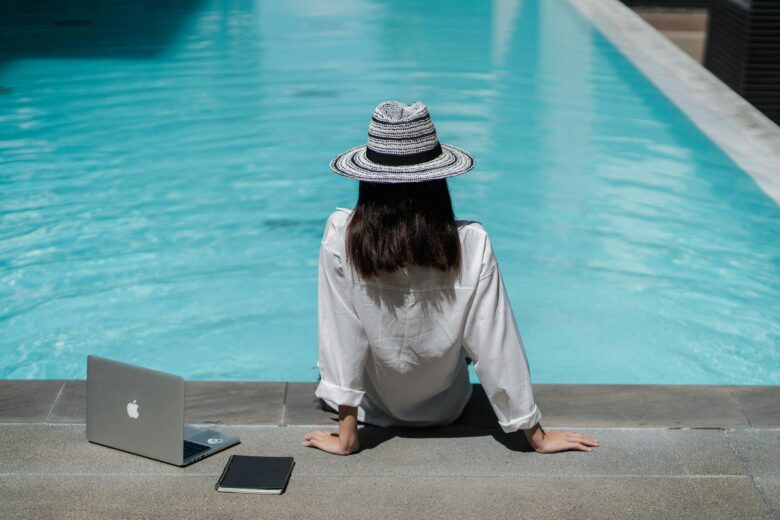 Digital nomad working remotely from a luxury all-inclusive resort in Morocco, near Marrakech, with a laptop by a sunlit pool, illustrating ideal telework and work-life balance.